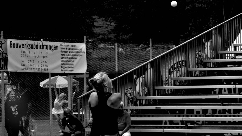 Hechingen 2016. The Morderger twins simultaneously playing on different courts, with their mother watching (lower left corner) and the constantly bleating sheep flock grazing on the slope behind that chain-wire fence. One of those lucky moments.